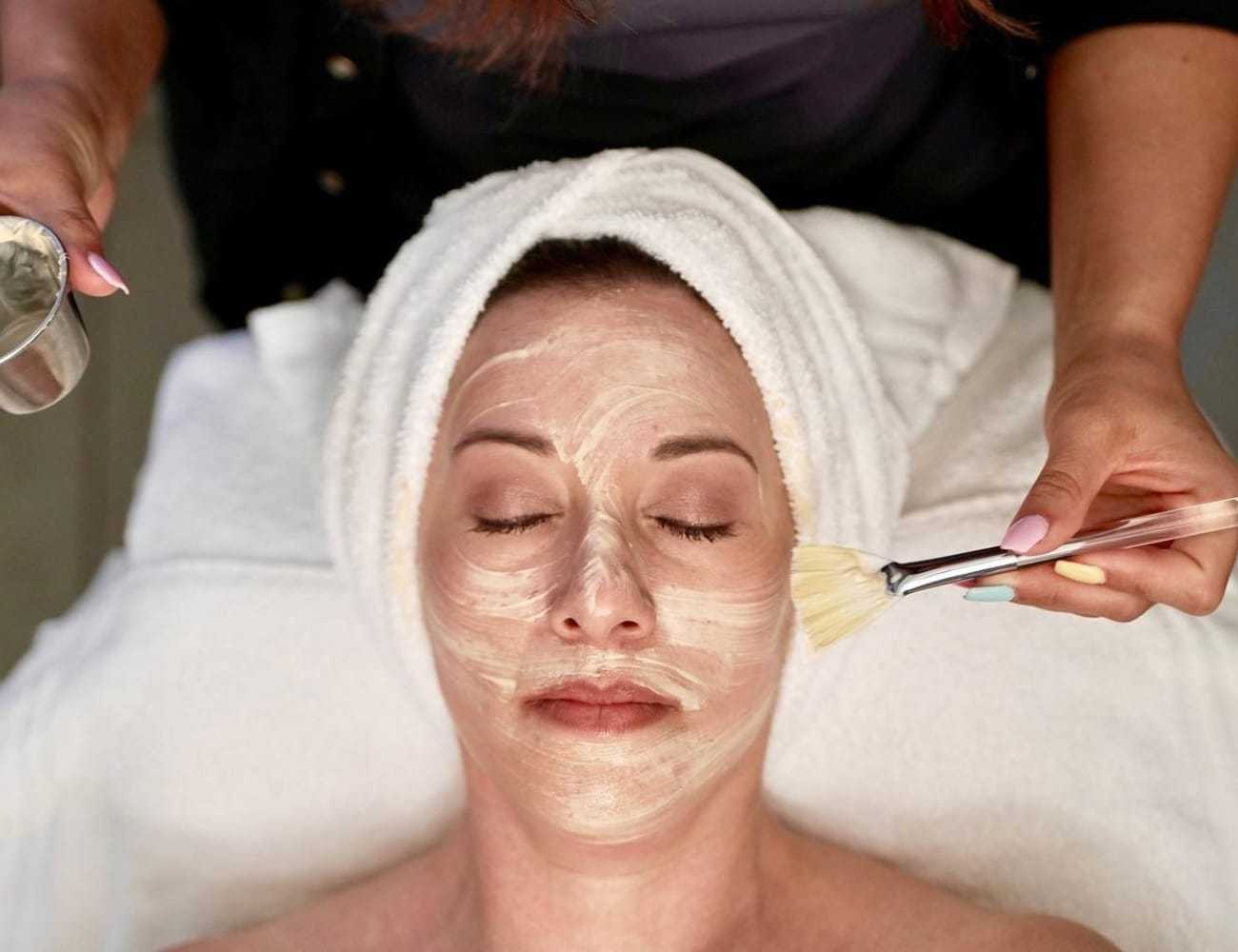 Facial treatment in progress at a spa, with a person applying a facial mask.